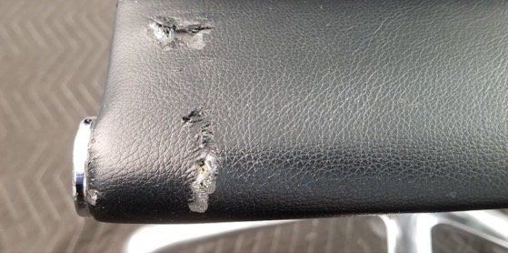 A close up of a black leather chair with holes in it.