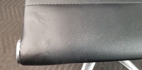 A close up of a black leather chair on a carpet.