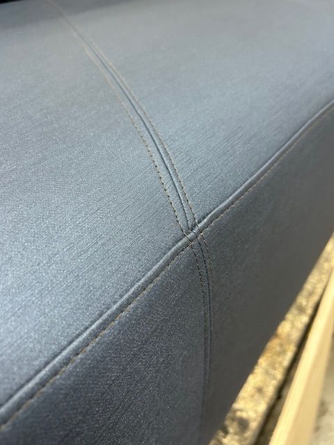 A close up of a gray couch with a stitched edge.