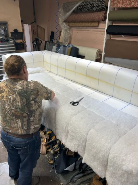 A man is working on a couch in a shop.