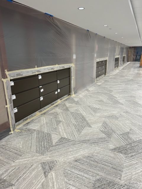 A long hallway with a carpeted floor and a wall covered in plastic.