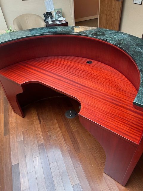 A red wooden desk with a green counter top is sitting on a wooden floor.