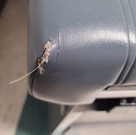A close up of a blue leather chair with a hole in it.