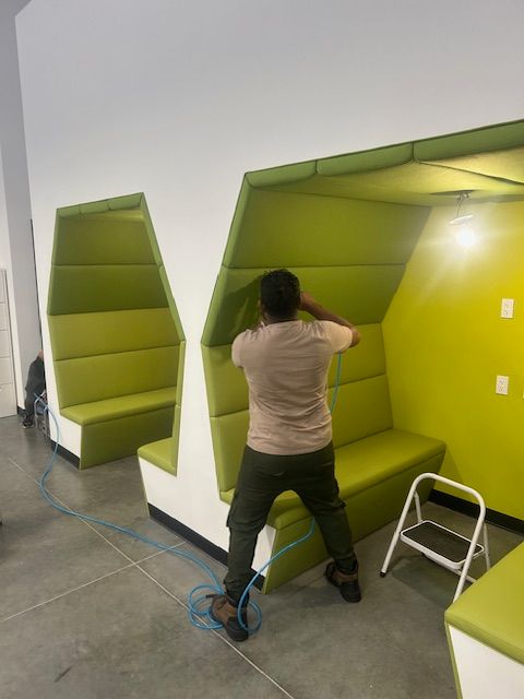 A man is standing in a room with green benches and a ladder.