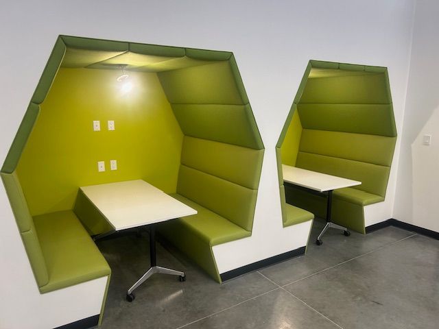 Two green booths with tables in them in a room