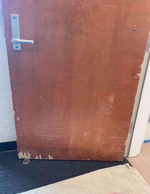 A dining room table is being painted in a room with a chandelier.