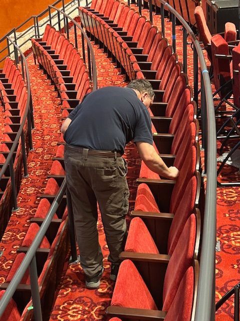 Person refinishing theater chairs