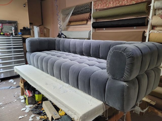 A grey couch is sitting on a bench in a room.