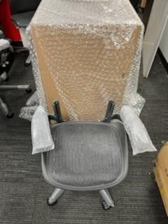 A chair is sitting in front of a box wrapped in plastic bubble wrap.