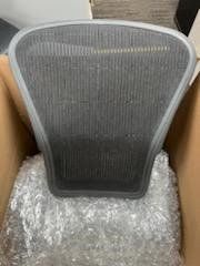 A chair seat is sitting in a cardboard box.