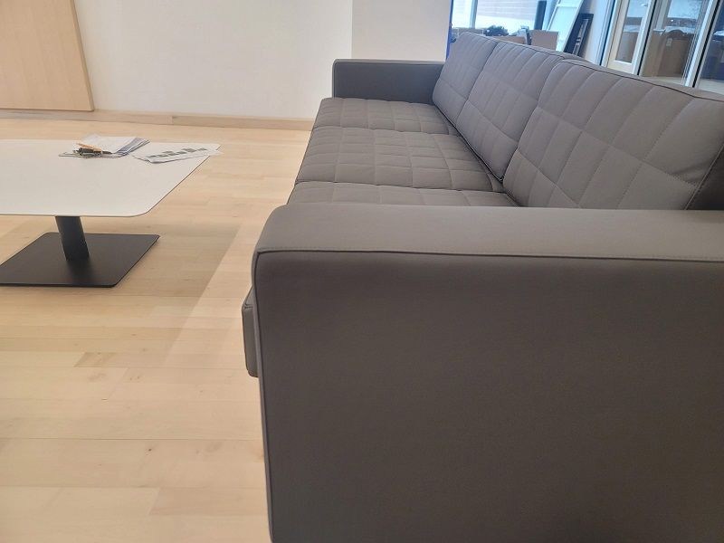 A gray couch is sitting next to a white wall.