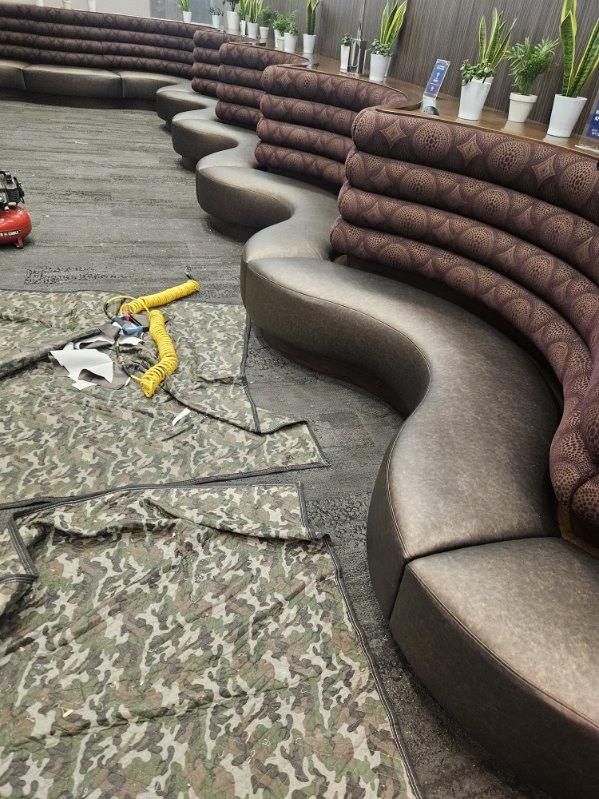 A curved brown sofa with camouflage fabric laid out nearby, in a restaurant/bar.
