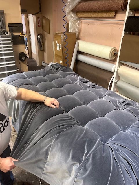 A person is holding a piece of fabric over a bed.