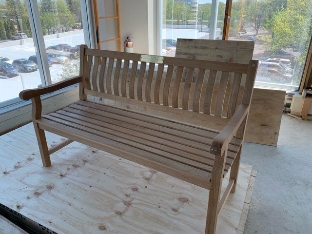 A wooden bench is sitting in front of a window