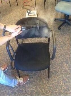 A person is cleaning a chair with a steam cleaner.