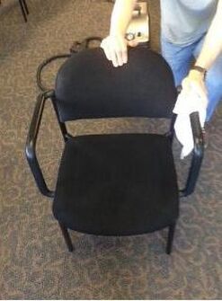 A person is cleaning a black chair with a cloth.