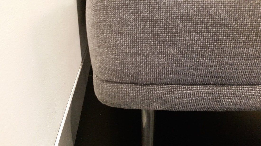 A gray couch is sitting next to a white wall.