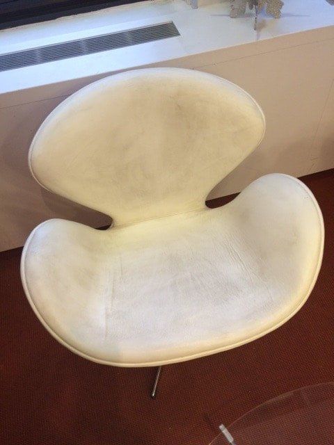 A white chair is sitting in front of a window