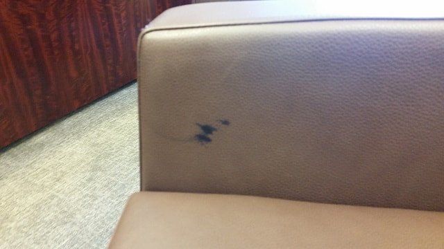 A brown leather couch with a stain on it