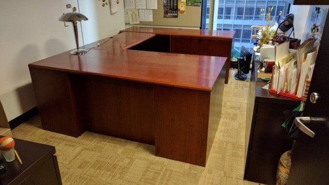 A wooden desk in a room with a lamp on it