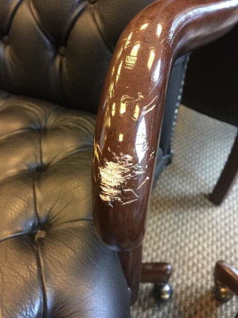 A black leather chair with a broken arm rest