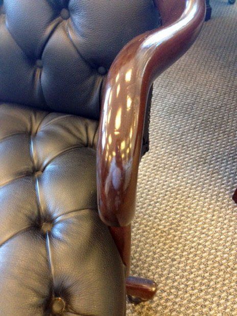 A black leather chair with a wooden arm rest