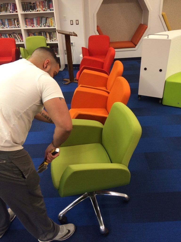 A man is cleaning a green chair in a library