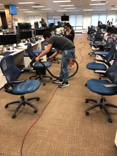 A man is vacuuming office chairs in an office