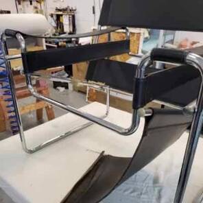 A black chair is sitting on top of a white table.