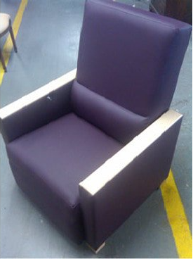 A purple chair with wooden arm rests is sitting on a concrete floor