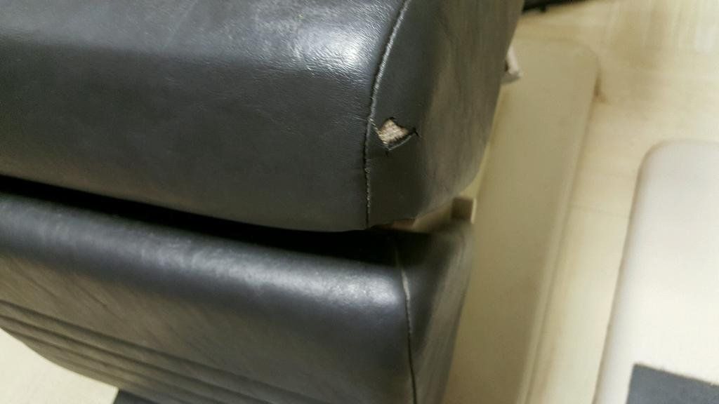 A close up of a black leather chair with a hole in it