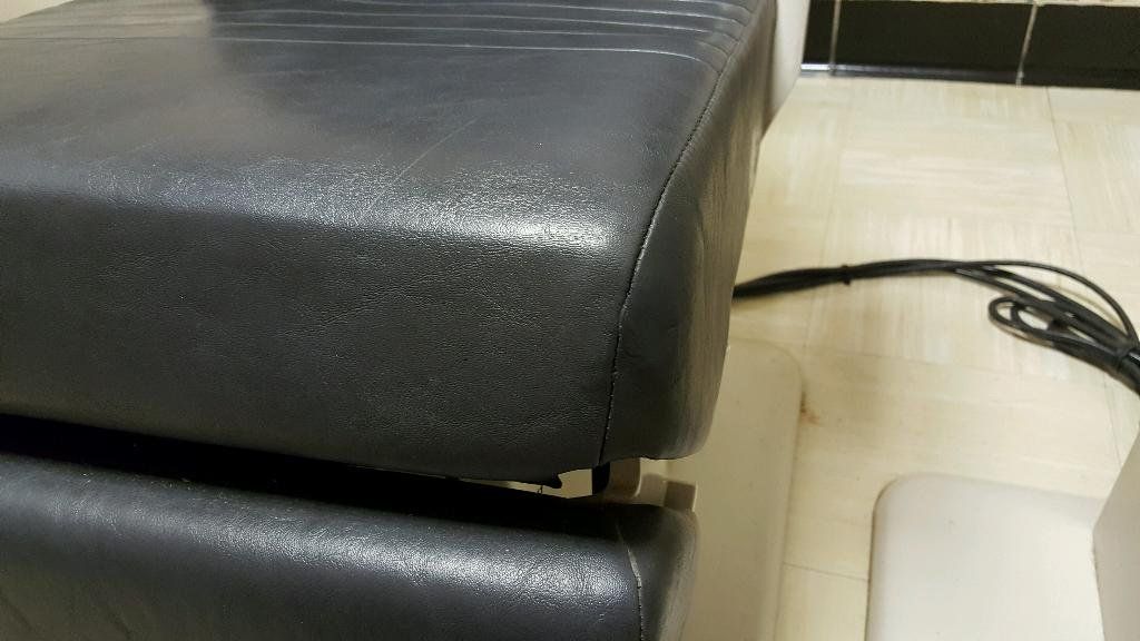 A close up of a black leather chair with a cord attached to it.