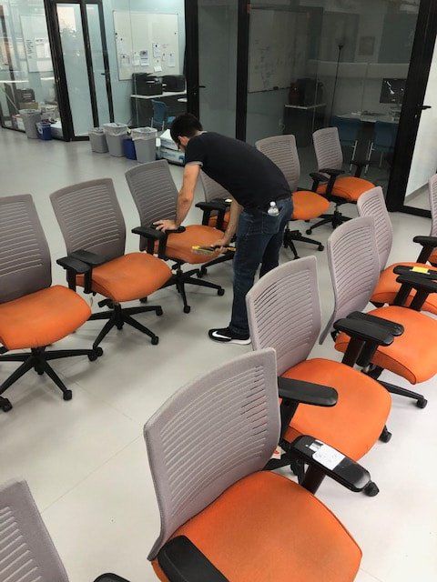 A man is cleaning a row of office chairs