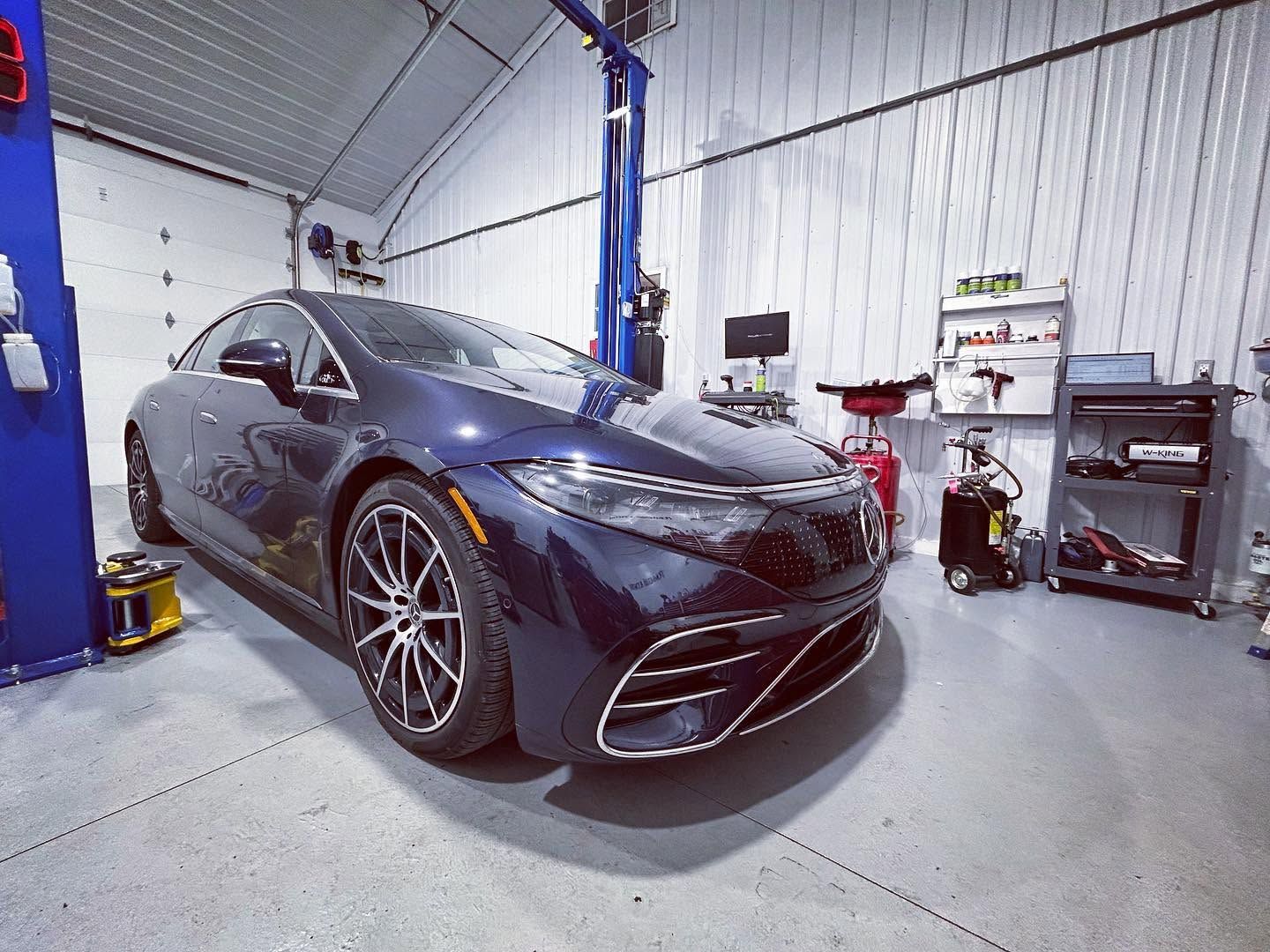 Black sports sedan in a garage on a lift, front-left view, with tools and equipment nearby | Pommerer's Automotive