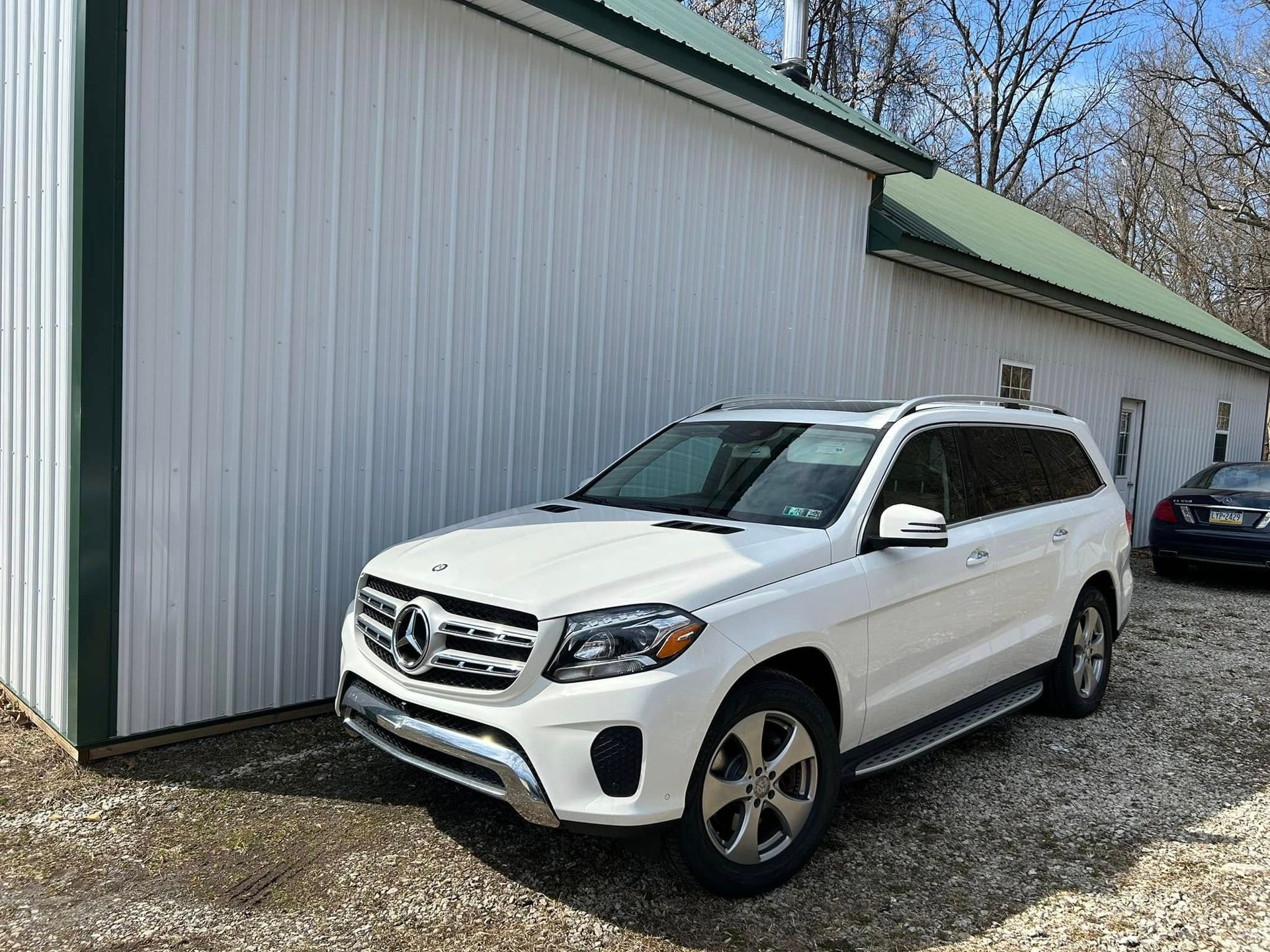 White Mercedes SUV parked beside a metal-sided building on a gravel lot. | Pommerer's Automotive