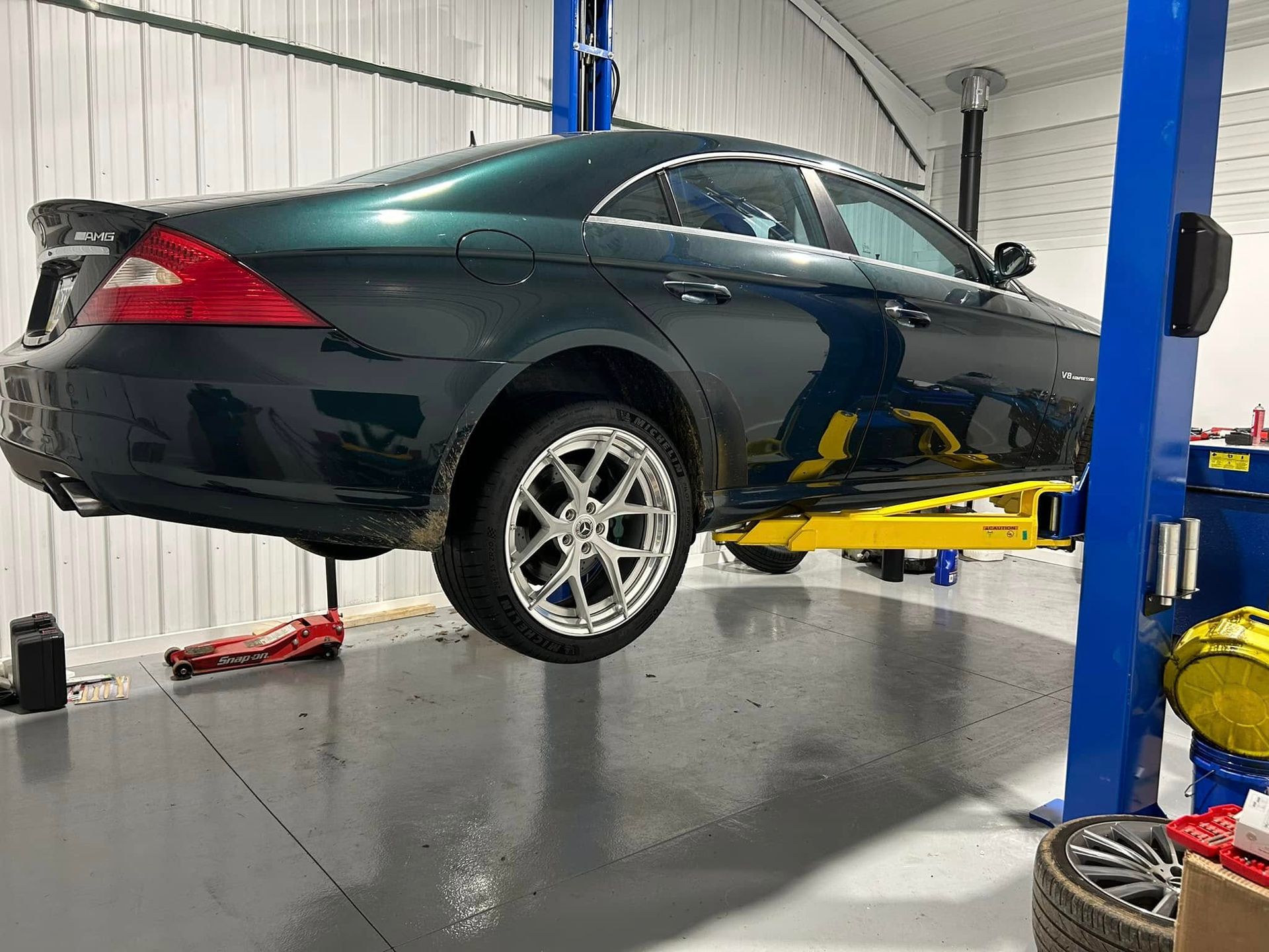 Dark green sedan raised on a car lift in an auto repair shop | Pommerer's Automotive