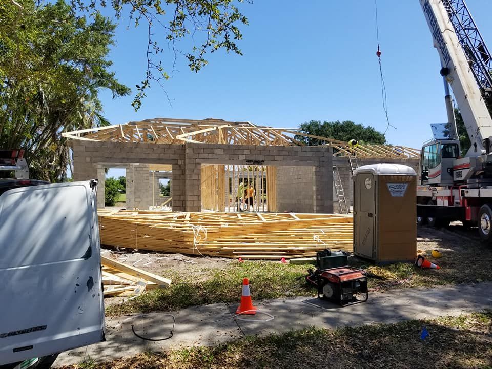 A white van is parked in front of a house under construction.