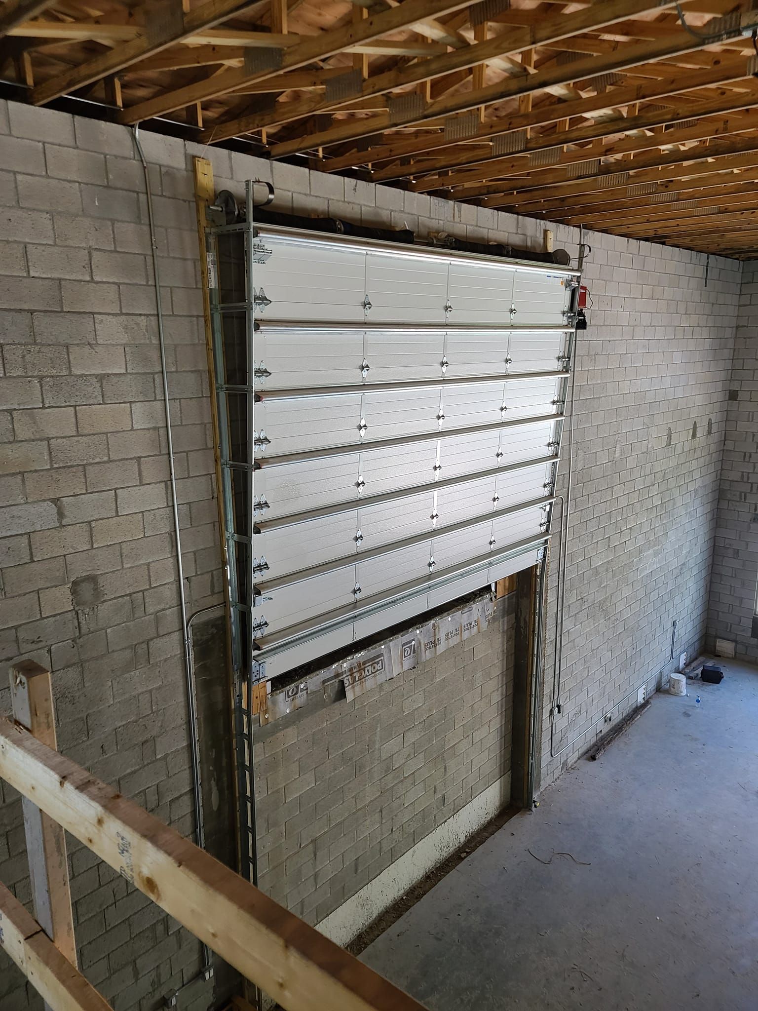 A garage door is being installed in a brick wall.