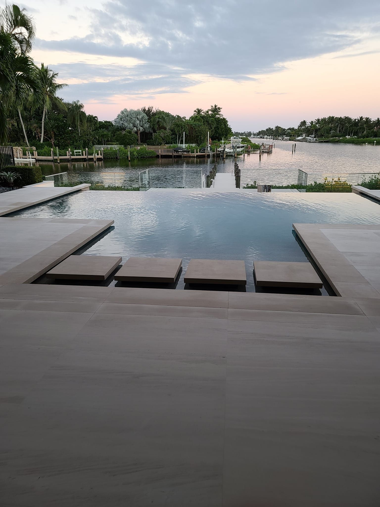 A large swimming pool surrounded by a wooden deck overlooking a body of water.