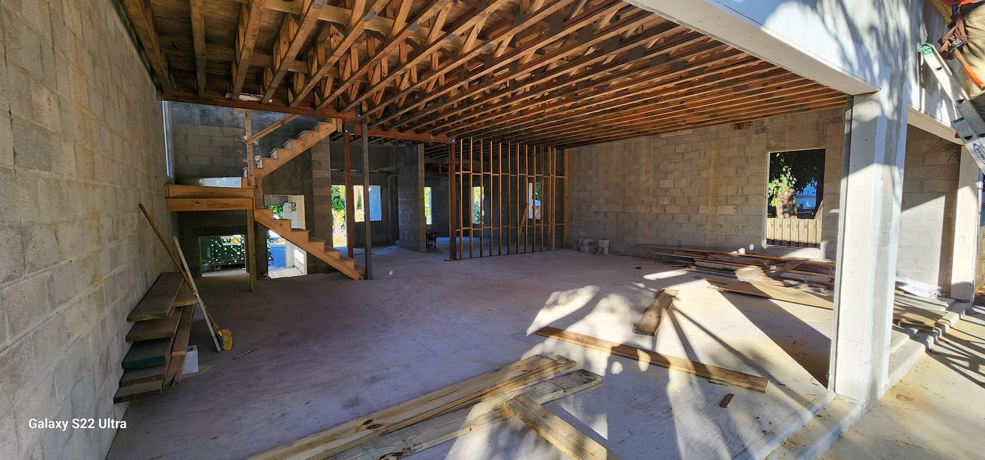 The inside of a building under construction with wooden beams and stairs.