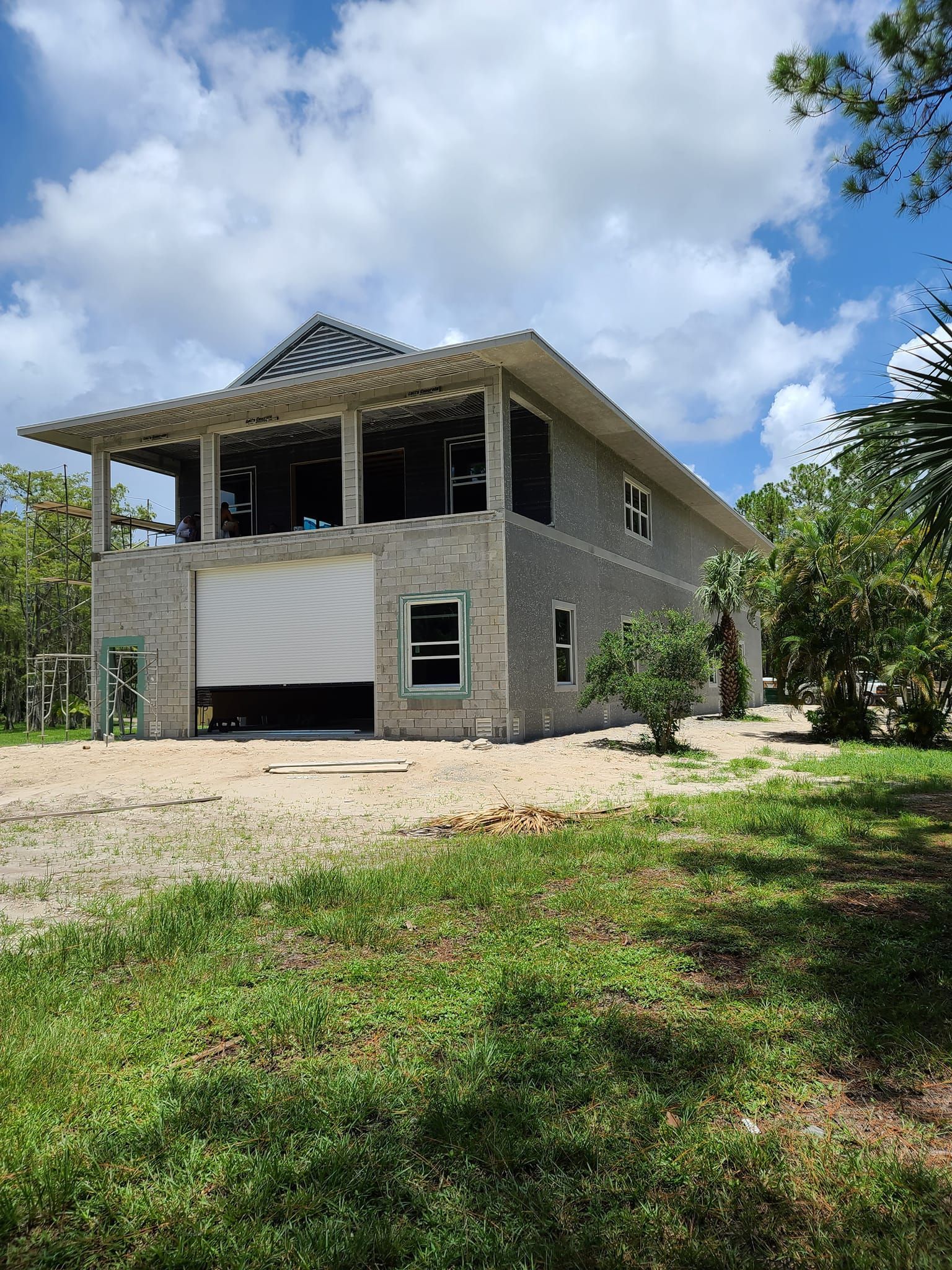 A large brick house is being built in the middle of a grassy field.