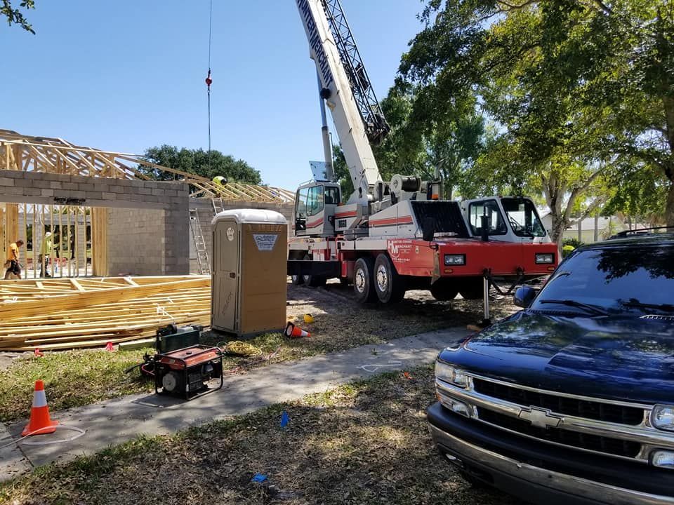 A truck is parked in front of a construction site with a crane.