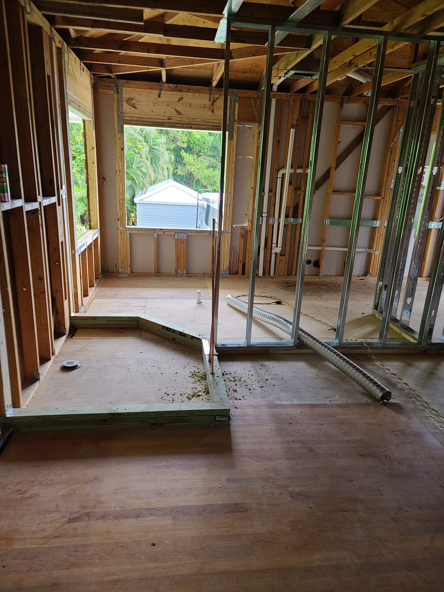 A room under construction with a wooden floor and a window.