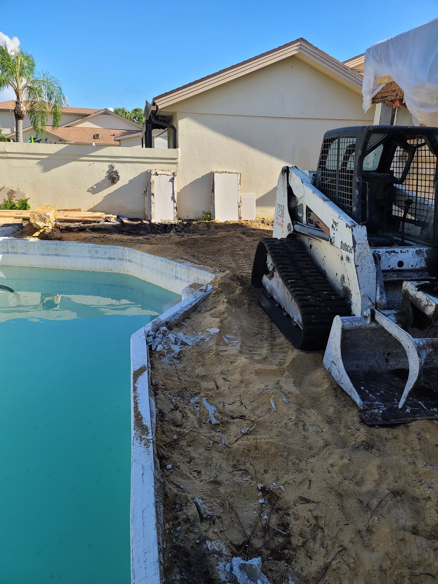 A bulldozer is sitting next to a swimming pool.