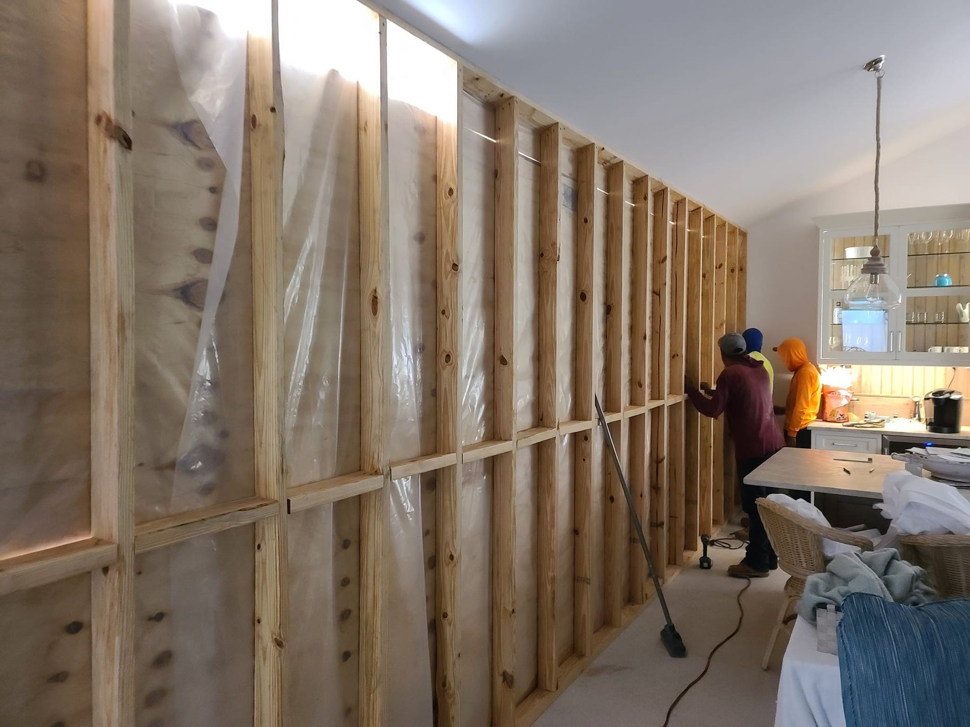 A couple of people are working on a wall in a room.