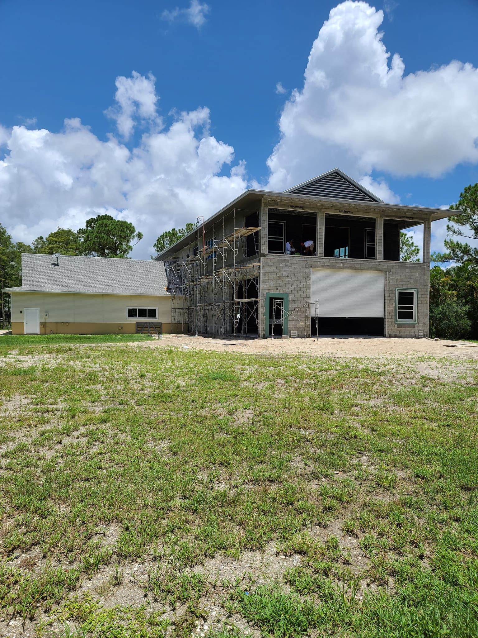 A large house is being built in the middle of a grassy field.