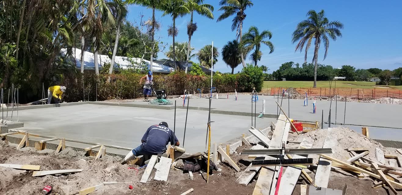 A construction site with a lot of concrete and palm trees in the background.