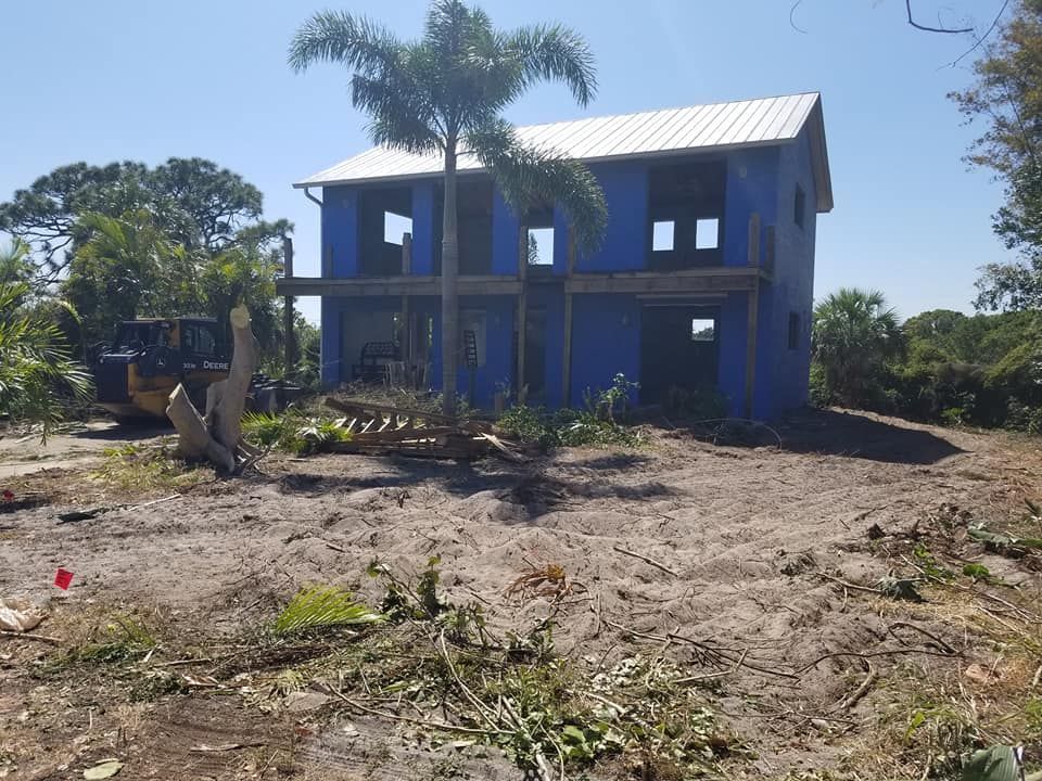 A blue house is being built in the middle of a dirt field