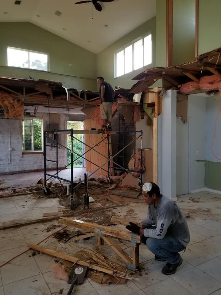 A man is kneeling down in a room with a hammer in his hand.