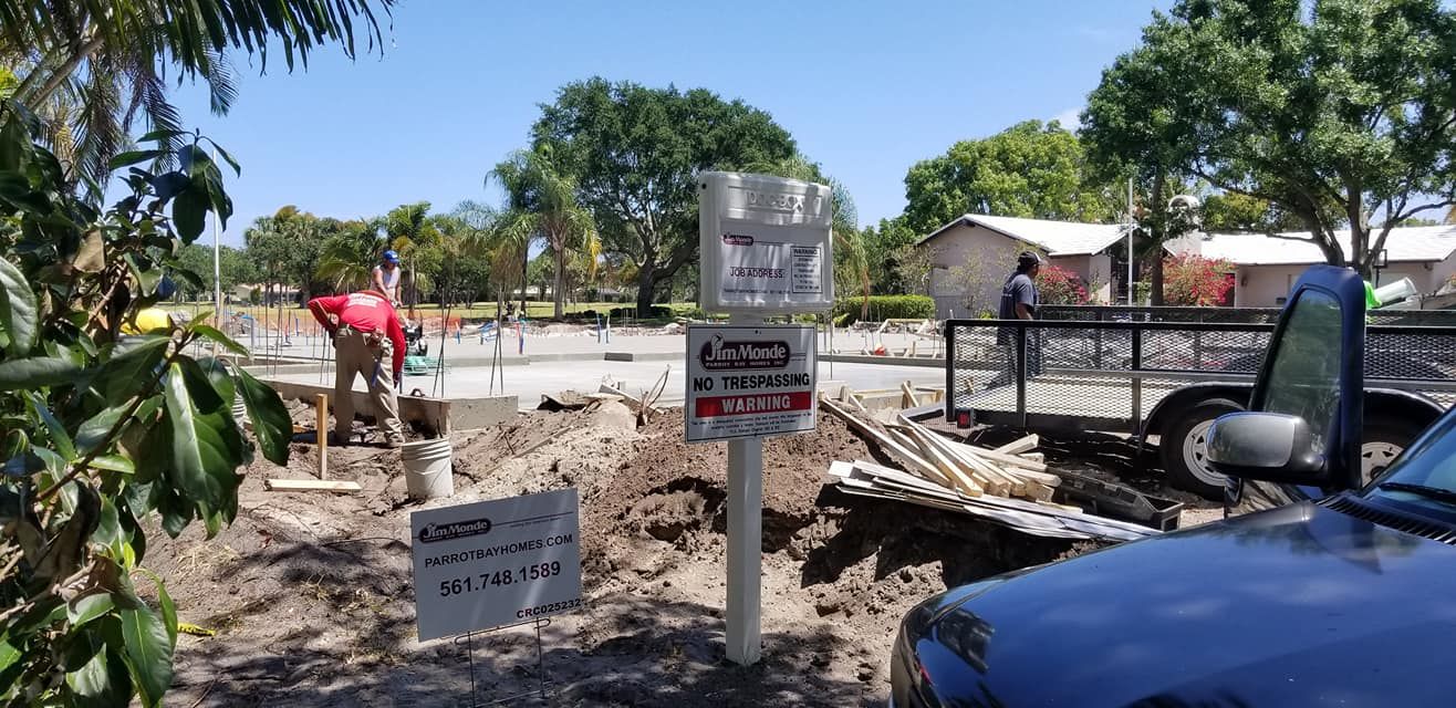 A black car is parked in front of a construction site.
